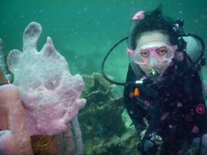 Kirana diving underwater near coral